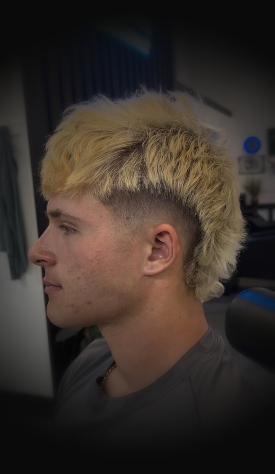 Blonde mullet beneath the shop's neon sign